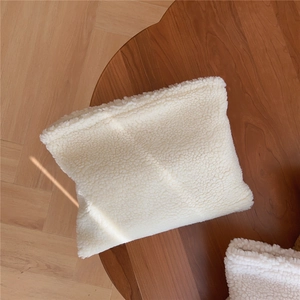 Detail shot of the plush white faux shearling texture on a minimalist handbag