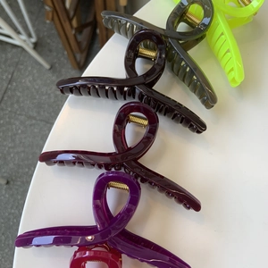 Macro detail of large colorful resin hair claws with strong golden metal springs