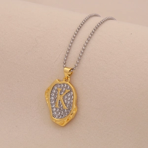 Macro detail of a gold letter K pendant with sparkling crystals on a bead chain necklace