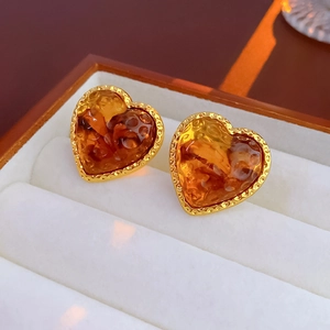 Macro detail of amber resin heart studs with gold edges in a white velvet box