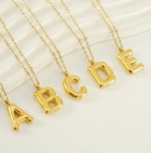Detailed shot of 3D balloon alphabet pendants A to E in polished gold with cross chains