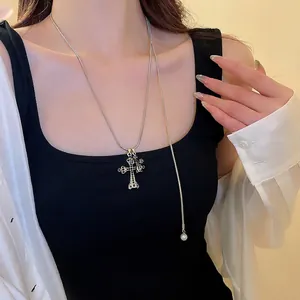 Collana con ciondolo a croce d'argento e strass neri indossata da una modella trendy