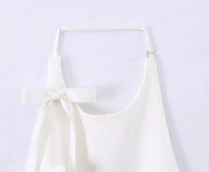 Detail of white halter neck top featuring a decorative bow and adjustable metal buckle