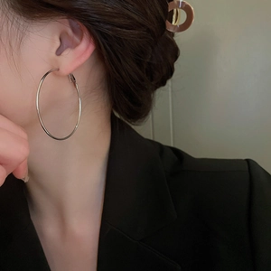 Vue latérale du mannequin portant des boucles d'oreilles créoles argentées minimalistes