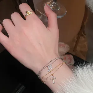French zircon cross and star bracelet with gold star ring on female hand in warm setting