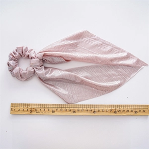 Detailed view of pink metallic hair scrunchie with long ribbons and pleated texture fabric