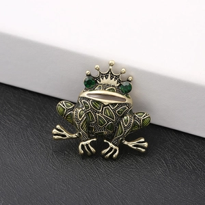 Vintage bronze frog brooch with green enamel and crown detail on black background