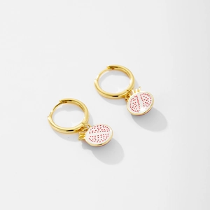 Detailed close-up of gold-plated hoop earrings featuring sliced pomegranate fruit charms