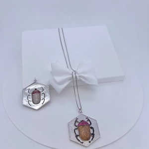 Macro view of micro-pave copper beetle pendants with colorful gemstones on a white stand