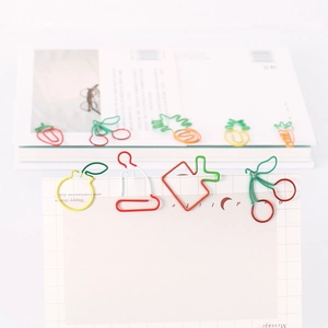 Creative fruit and vegetable shaped paper clips on white grid notes for office