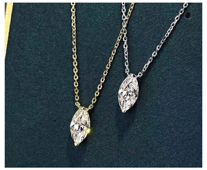 Macro detail of gold and silver necklaces featuring marquise cut zircon pendants on a blue base