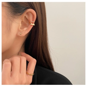 Detail of gold double-layer ear cuff and bead earring set on model's ear