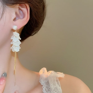 Detailed view of long gold fringe earrings with layered white petals and pearls