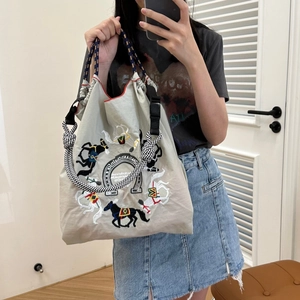 Close-up of light gray drawstring tote bag featuring horse embroidery and rope handle
