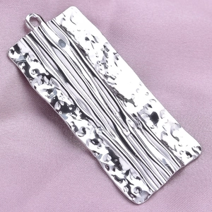 Macro shot of silver hammer-textured rectangular pendant with polished line details