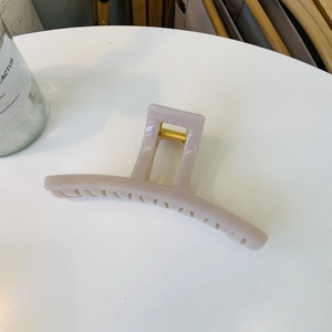 Detail of a large cream resin hair claw clip with a strong gold metal spring for styling