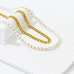 Detail of gold chain necklace with white pearl pendant wrapped around a Roman column