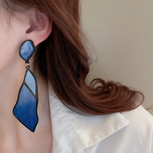 Detail view of large geometric acrylic earrings with blue marble texture on model