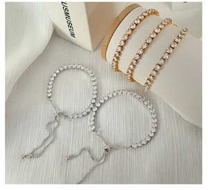 Detail of adjustable zircon tennis bracelets in gold and silver finish with slide clasp
