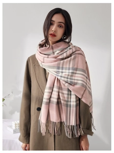 Detail showing pink and grey plaid scarf with fringes on a female model wearing a coat