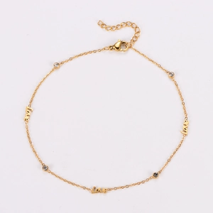 Close-up of golden anklet with LOVE letter charm and sparkling crystal rhinestones
