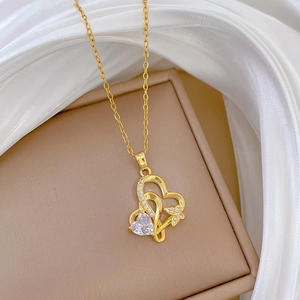 Détail macro du pendentif double cœur doré avec nœud papillon et cristaux brillants