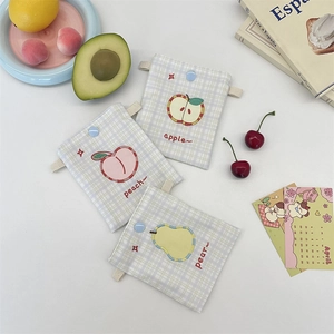 Close-up of small plaid fabric pouches with cute fruit embroidery and snap button closure