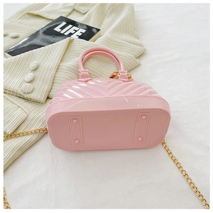 Detailed view of pink wavy jelly bag with gold chain strap on corduroy fabric