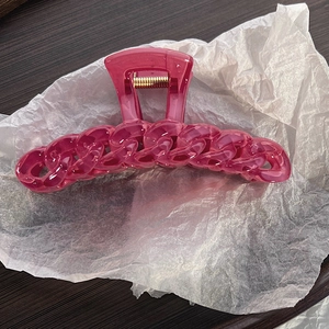 Close-up of translucent pink chain hair claw clip with strong golden metal spring