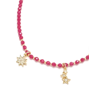 Macro detail of Bohemian agate beaded necklace with gold star pendants and red beads