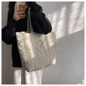 Mirror selfie showing the large capacity cream white puffy tote bag with soft padding