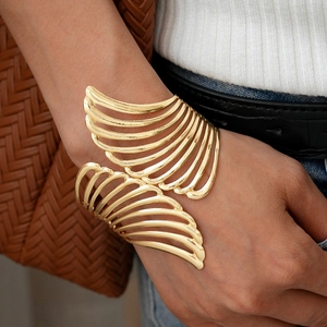 Close-up of golden hollow wing cuff bracelet on wrist with elegant metallic texture