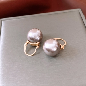 Gros plan de perles de verre gris-mauve sur créoles dorées dans un coffret à bijoux