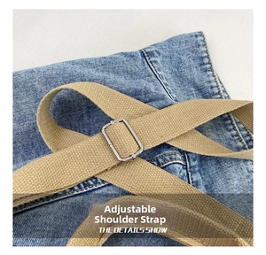 Detail of adjustable khaki woven strap with silver metal buckle on blue denim tote bag