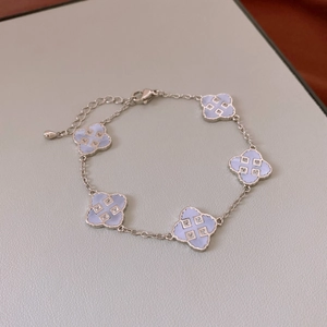 Close-up of a silver four-leaf clover bracelet with light blue inlays and lobster clasp