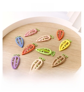 Detailed view of hollow carrot-shaped hair clips in nine candy colors on a wooden tray