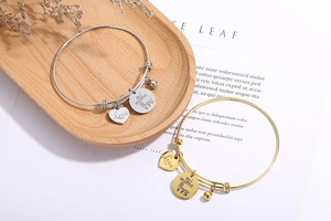 Detail of silver and gold heart bracelets with Love mi mama charms on wooden tray