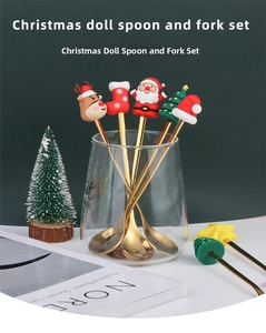 Close-up of golden Christmas spoons and forks with festive silicone charms in a glass cup
