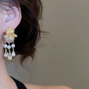 Detail showing vintage gold rose earrings with layered pearls and crystal tassels on model