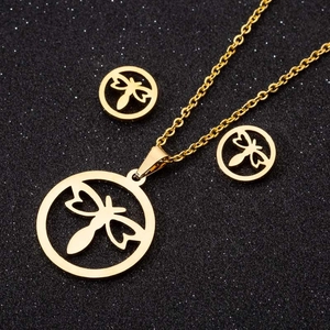 Close-up of a gold dragonfly pendant necklace and stud earrings set on a black background