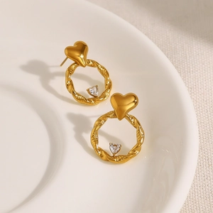 Elegant gold twist heart earrings with sparkling zircon drop pendants on white tray
