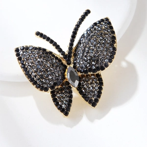 Macro di una spilla a farfalla con strass grigi su uno sfondo bianco pulito