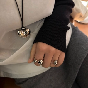 Polished silver heart pendant necklace and minimalist sphere rings on a model