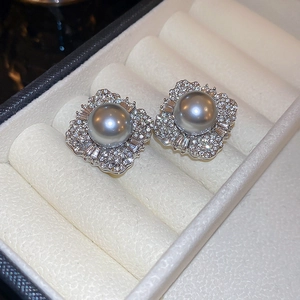 Macro shot of gray pearl earrings with zircon petals in an ivory jewelry display box
