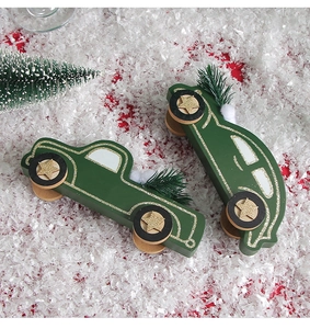 Detail shot of forest green wooden Christmas car ornaments with gold stars on white snow