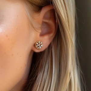 Close-up of a model wearing a gold round pavé cluster earring with sparkling zircons