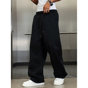 Close-up of black loose-fit cotton joggers with elastic waist on a male model