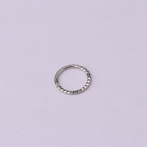 Detailed view of silver stainless steel septum ring with pyramid stud texture and hinge