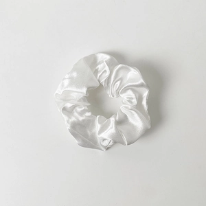 Detailed view of the smooth white satin fabric and pleated texture of the scrunchie