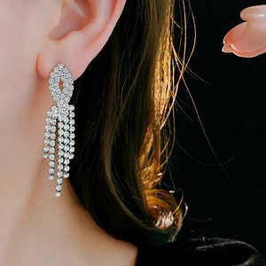 Detail of silver leaf-shaped earrings with shimmering rhinestone tassels on a model